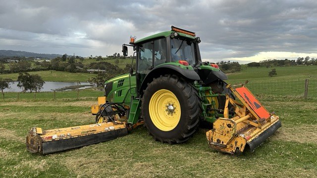 Alamo Interstater side and rear flail decks working a paddock beside a dam
